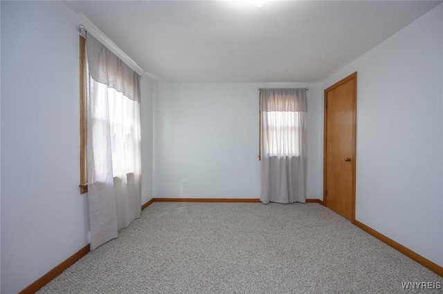 unfurnished room with light colored carpet and baseboards