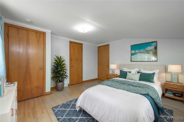 bedroom with baseboards, vaulted ceiling, and light wood-type flooring