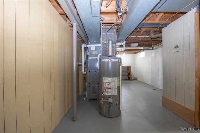 below grade area featuring wood walls and gas water heater