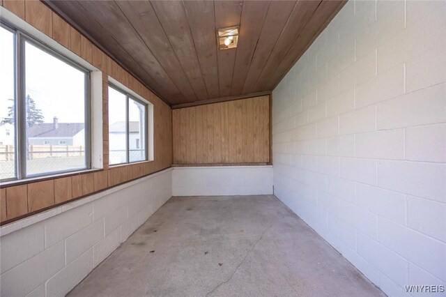 interior space with concrete block wall, concrete flooring, and wooden ceiling