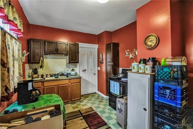 kitchen featuring light floors, baseboards, and a sink