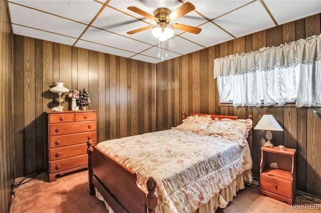carpeted bedroom featuring wooden walls and a ceiling fan
