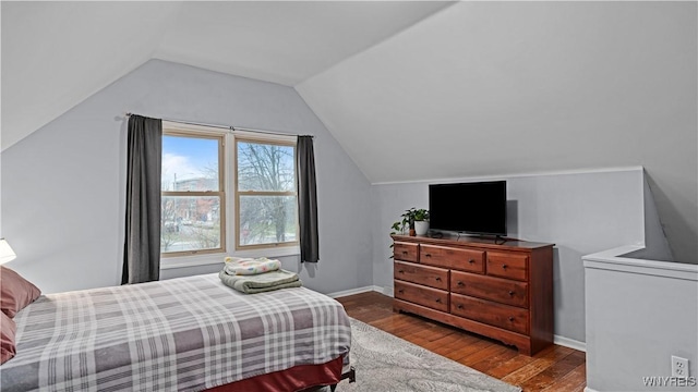 bedroom with baseboards, wood finished floors, and lofted ceiling