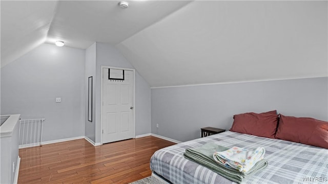 bedroom with baseboards, wood finished floors, and lofted ceiling