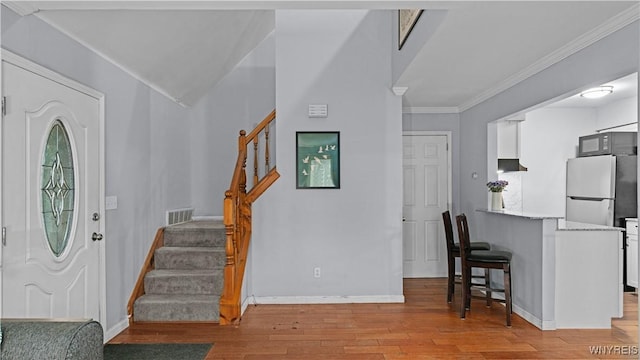 entrance foyer featuring visible vents, stairway, baseboards, ornamental molding, and light wood-style flooring