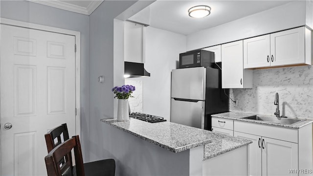 kitchen with white cabinets, black microwave, a sink, freestanding refrigerator, and tasteful backsplash