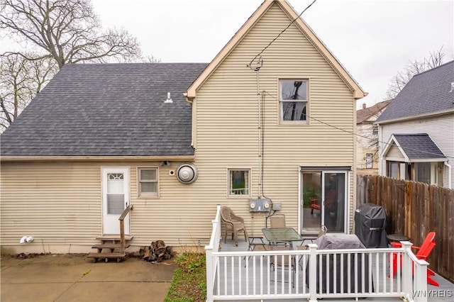 back of house with roof with shingles, fence, a deck, and entry steps