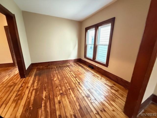 empty room with baseboards and hardwood / wood-style flooring