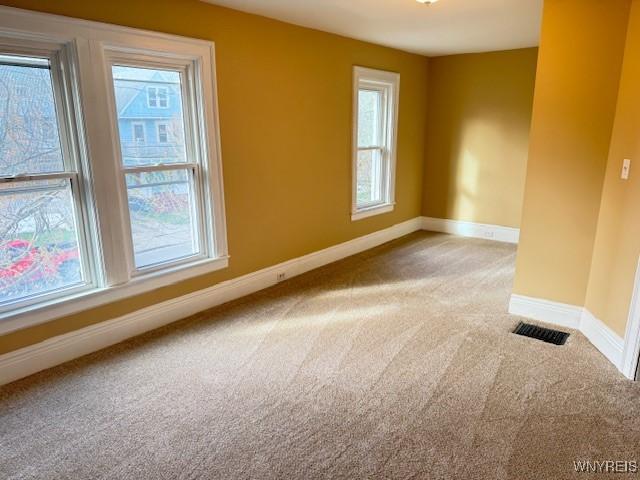 unfurnished room featuring visible vents, carpet, and baseboards