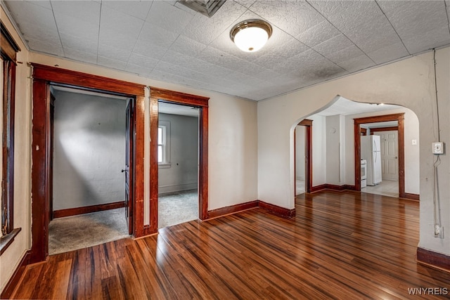 spare room featuring visible vents, hardwood / wood-style floors, baseboards, and arched walkways