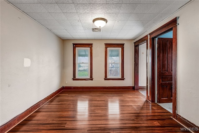 empty room with visible vents, dark wood-style floors, and baseboards