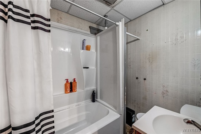 bathroom with shower / bath combo, a sink, and tile walls