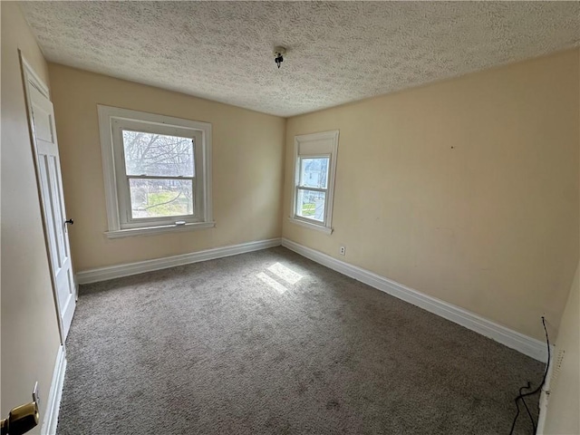 empty room with a textured ceiling, carpet flooring, and baseboards