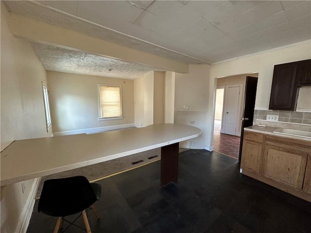 kitchen with a sink, tasteful backsplash, a breakfast bar, dark floors, and light countertops