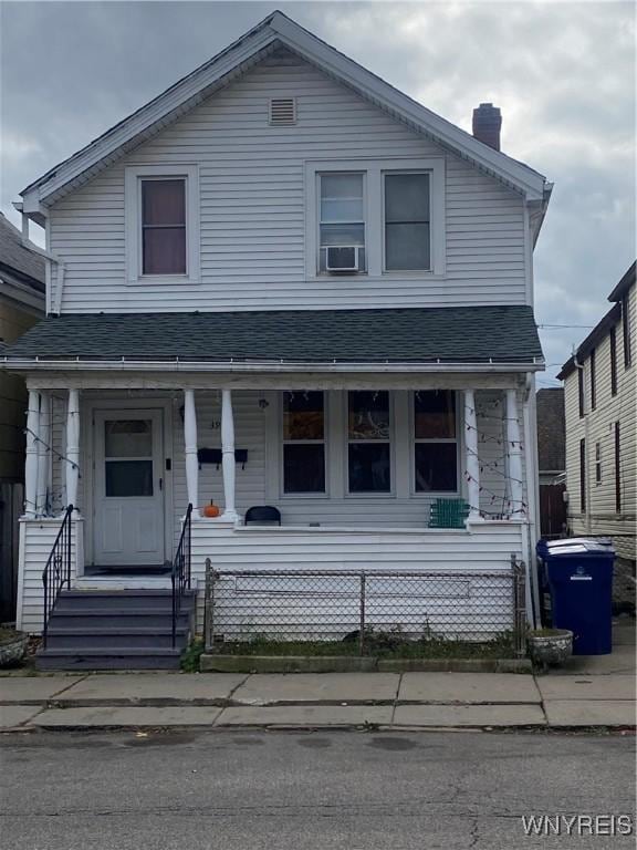 view of front of home with roof with shingles, covered porch, a chimney, and cooling unit