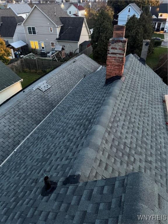details featuring a residential view, roof with shingles, fence, and a chimney