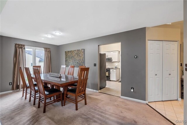 dining space featuring baseboards and light colored carpet