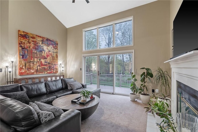 living room featuring a ceiling fan, high vaulted ceiling, and a fireplace with flush hearth
