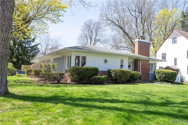 rear view of property with a yard, brick siding, and a chimney