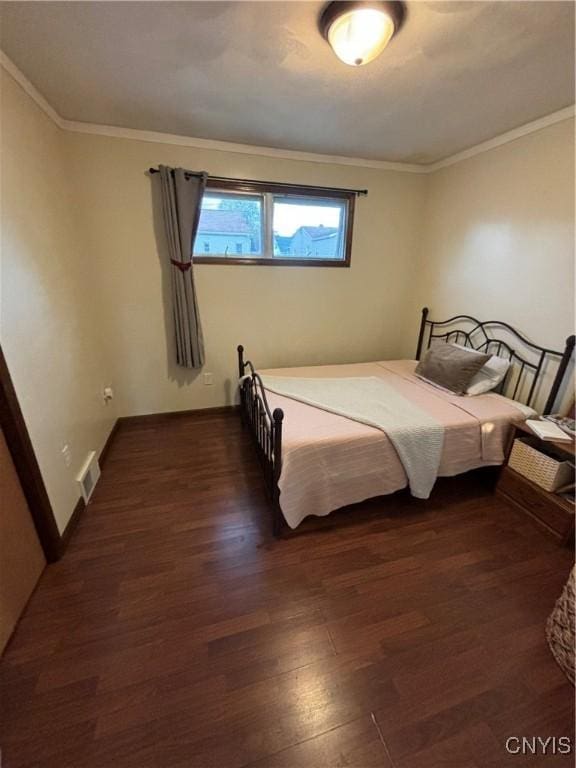 bedroom with baseboards, ornamental molding, wood finished floors, and visible vents