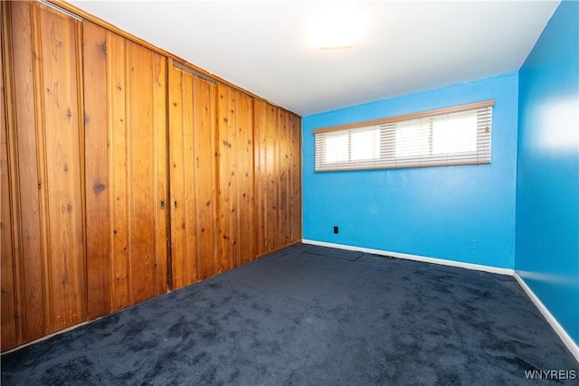 carpeted spare room with wooden walls and baseboards