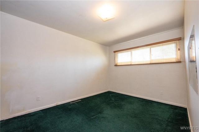 spare room featuring baseboards, dark carpet, and visible vents