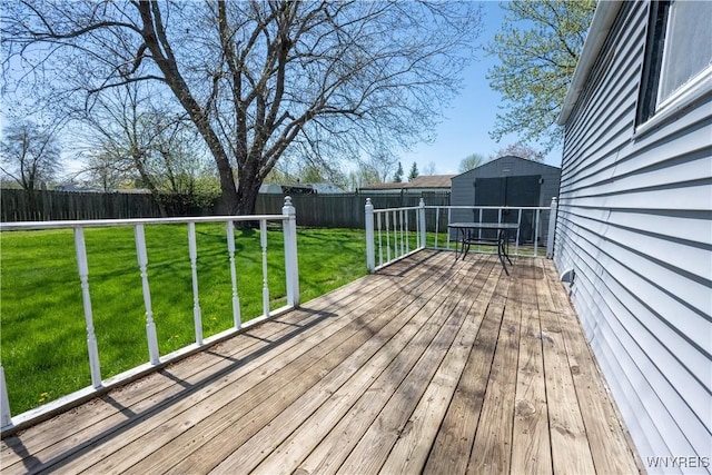 wooden terrace featuring a yard, an outdoor structure, a fenced backyard, and a storage unit