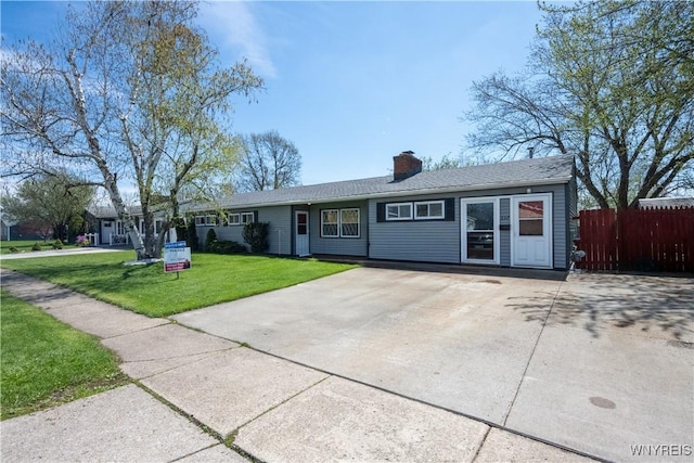 single story home featuring fence, a chimney, driveway, and a front lawn