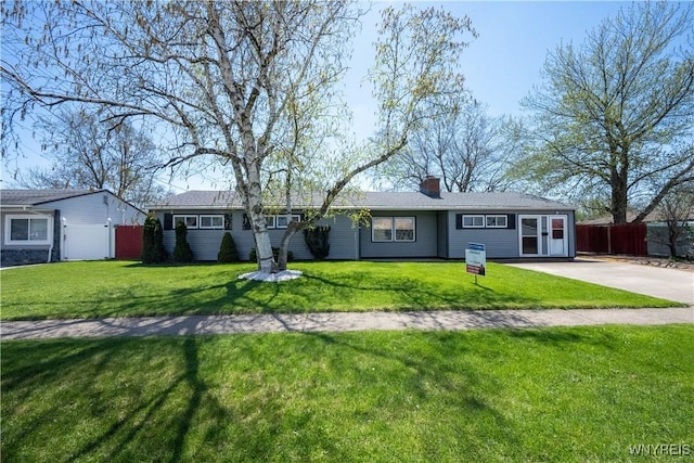 ranch-style home with fence, a chimney, and a front yard