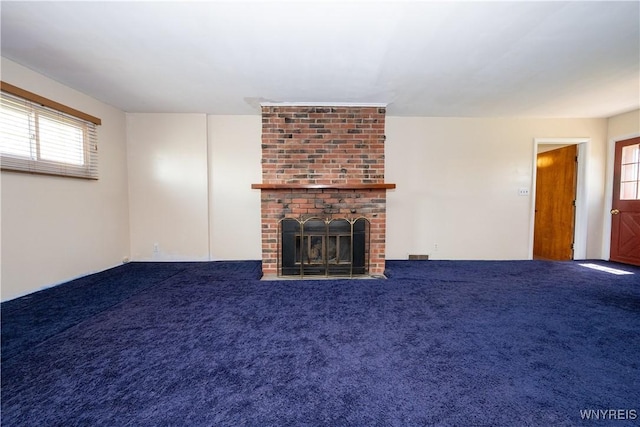 unfurnished living room with carpet floors, visible vents, a fireplace, and a wealth of natural light