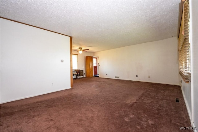 unfurnished room featuring a healthy amount of sunlight, carpet flooring, and a textured ceiling