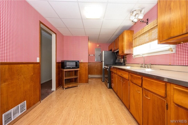 kitchen with visible vents, range with gas stovetop, black microwave, light wood-style floors, and wallpapered walls