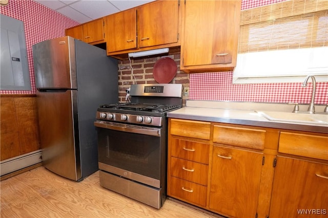 kitchen featuring brown cabinets, light countertops, stainless steel appliances, wallpapered walls, and a baseboard radiator