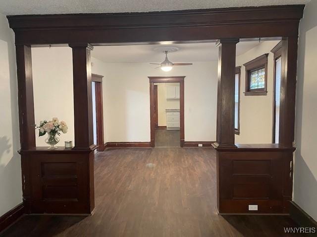 hall with baseboards, decorative columns, and wood finished floors