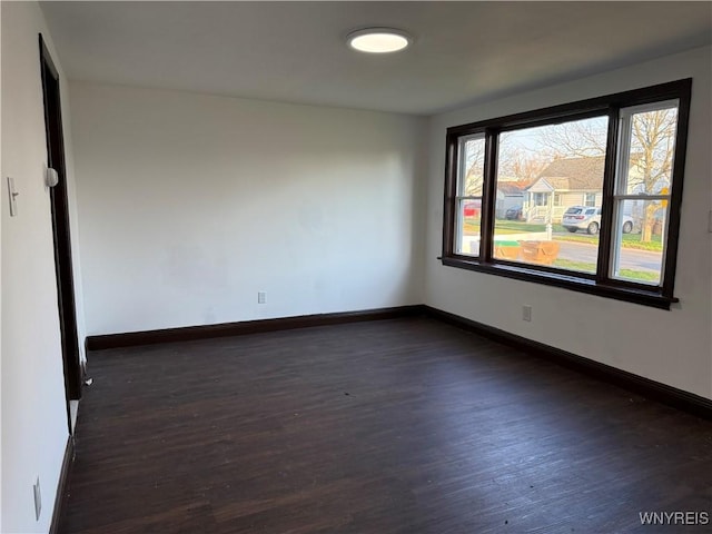 spare room featuring dark wood-style floors and baseboards
