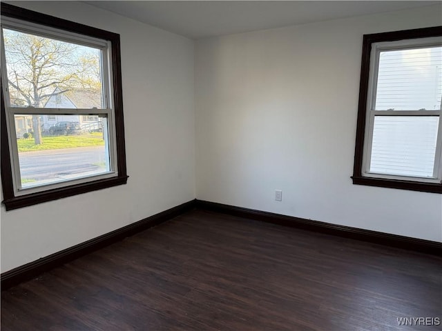 empty room with baseboards and dark wood-type flooring