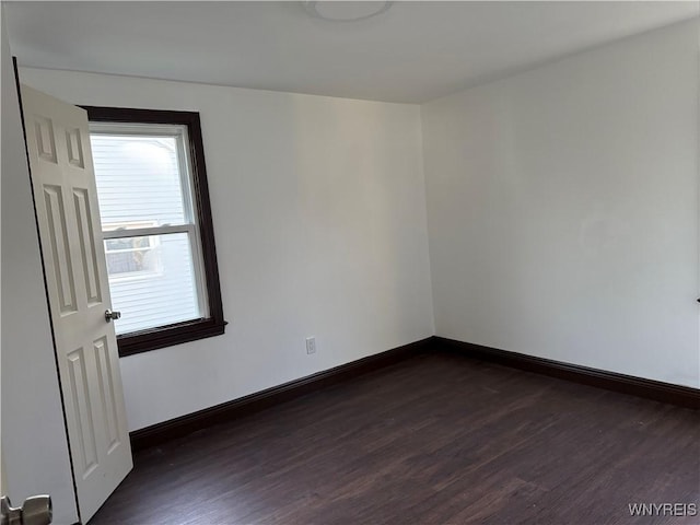 unfurnished room with baseboards and dark wood-type flooring