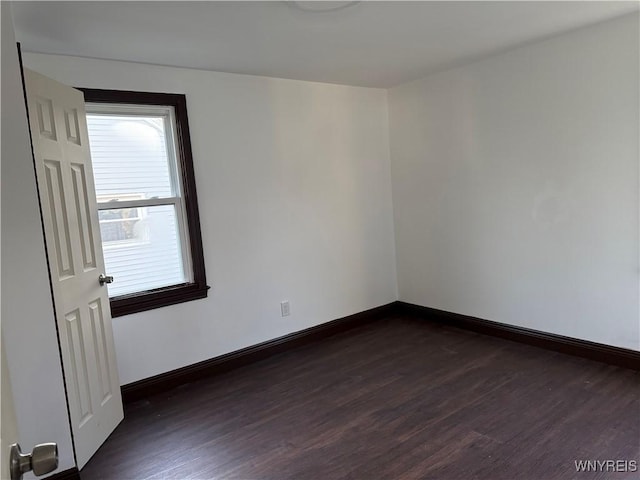 spare room featuring baseboards and dark wood-type flooring