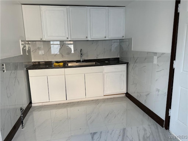 kitchen featuring white cabinets, dark countertops, and a sink