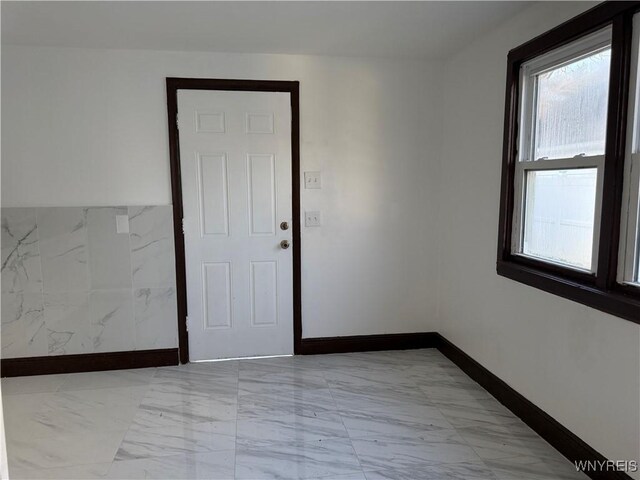 unfurnished room with marble finish floor and baseboards