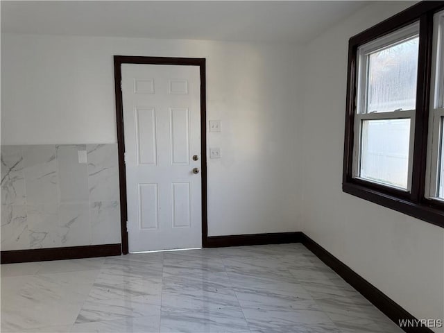 unfurnished room featuring marble finish floor and baseboards