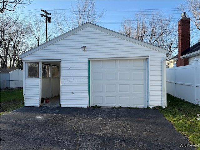 detached garage featuring fence and aphalt driveway