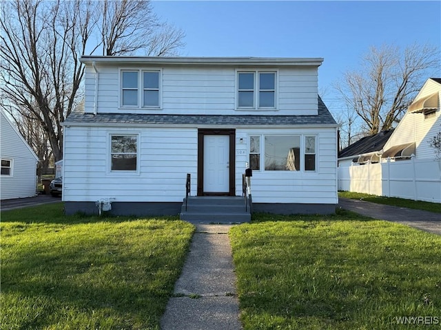 bungalow-style home with a shingled roof, fence, and a front lawn