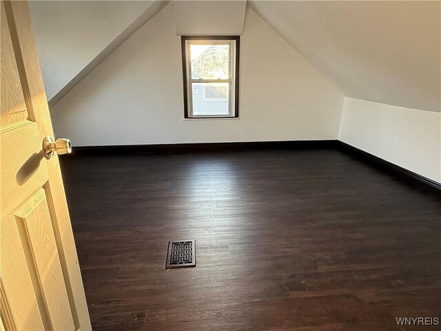 additional living space with lofted ceiling, wood finished floors, visible vents, and baseboards