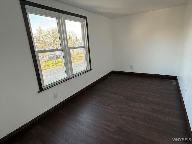 unfurnished room with dark wood-style floors and baseboards