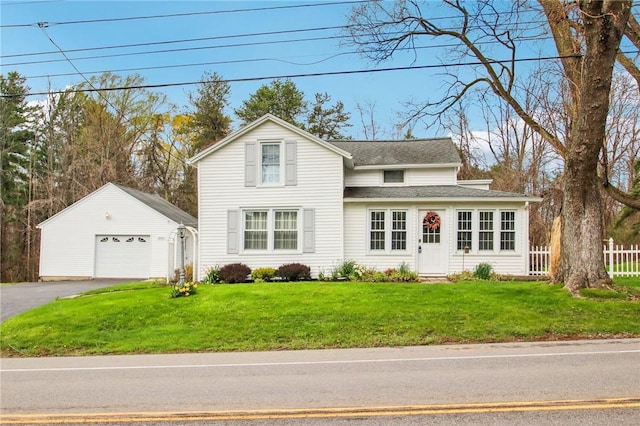traditional-style house featuring a front yard, an outdoor structure, a detached garage, aphalt driveway, and fence