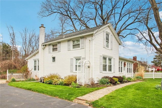 view of front of house featuring a front yard, a chimney, and fence