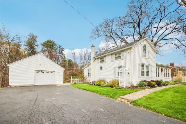 view of home's exterior with an outbuilding, a detached garage, a yard, and a chimney
