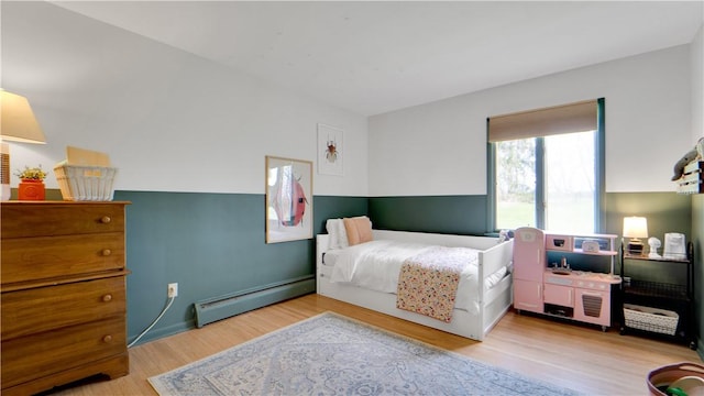 bedroom featuring light wood-style floors and a baseboard heating unit