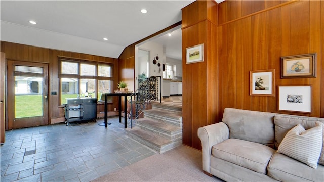 living area with stone tile flooring, wooden walls, stairway, recessed lighting, and vaulted ceiling